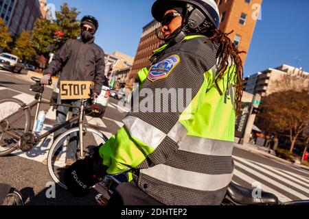 Washington, DC, USA, 11 dicembre 2020. Nella foto: Un poliziotto metropolitano (DC) che accompagna una protesta - non invitata - immediatamente dopo che ha colpito un ciclista con la sua moto. Ciò si è verificato durante una protesta per la consegna di una lettera da parte di donne indigene alle banche chiedendo che non finanziassero i gasdotti Keystone XL, Line 3 e Trans Mountain dalle sabbie bituminose canadesi a causa di danni ambientali e distruzione di terre indigene. Credit: Alison C Bailey/Alamy Live News Foto Stock