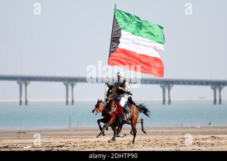 Governatorato di Jahra, Kuwait. 11 Dicembre 2020. Un uomo che detiene una bandiera del Kuwait cavalca un cavallo durante un'escursione a cavallo a Jahra Governorate, Kuwait, 11 dicembre 2020. I proprietari di cavalli arabi Kuwaitiani hanno tenuto uno spettacolo di equitazione il venerdì nel deserto del Governatorato di Jahra del Kuwait per introdurre la tradizione araba di equitazione. Credit: Ghazy Qaffaf/Xinhua/Alamy Live News Foto Stock