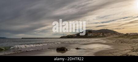 La spiaggia di Praia do Langosteira e la città di Fisterra in Galizia occidentale in calda luce notturna Foto Stock