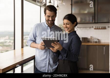 Sorridenti dipendenti diversi collaborano utilizzando il tablet in ufficio Foto Stock