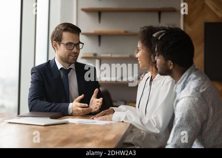 Il realtor maschile consulta la famiglia biraciale alla riunione Foto Stock