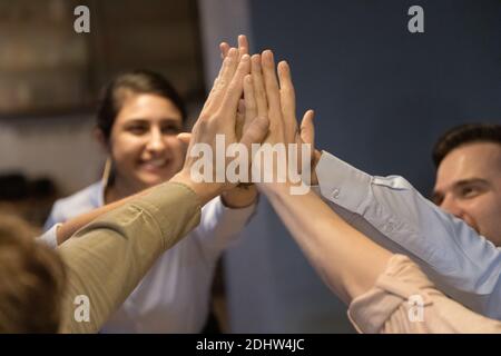 I dipendenti multirazziali entusiasti danno cinque in alto durante la riunione Foto Stock