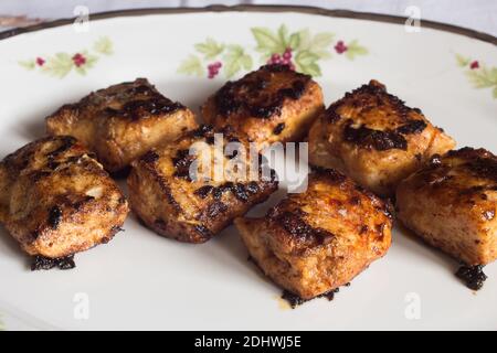 Primo piano di lombo di nasello in burro con aglio e paprika su un piatto vecchio decorato. Cibo e pesce. Foto Stock