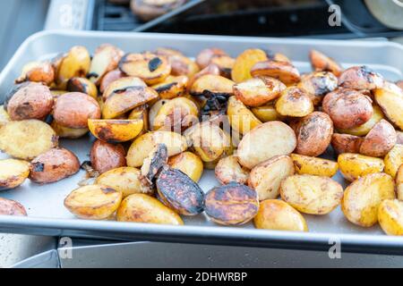 Grigliare piccole patate con fettine di aglio su una piscina grill a gas. Foto Stock