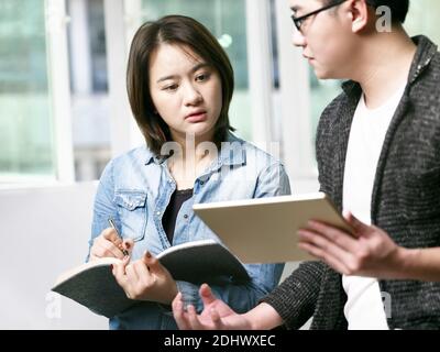 giovane asiatico uomo e donna che discute di affari in ufficio usando tablet digitale Foto Stock
