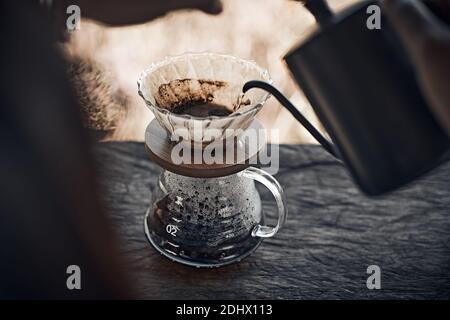 Mano caffè gocciolamento, Barista versando acqua sul caffè macinato con filtro Foto Stock