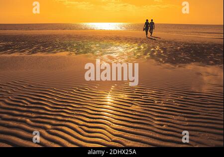 Paar wandert bei Ebbe am Strand, Sonnenuntergang, MR: SÌ Foto Stock