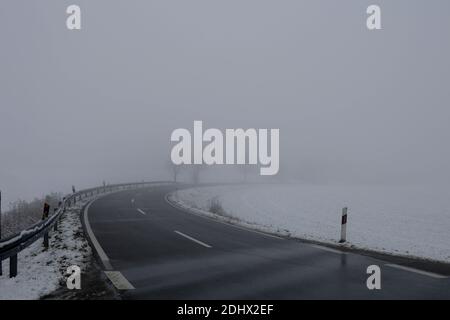 Pericoloso tratto di strada su una mattina invernale nebbiosa. Foto Stock