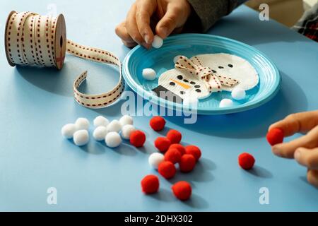 Bambino piccolo che gioca con il nastro e pom pom fare un Pupazzo di neve di Natale Foto Stock