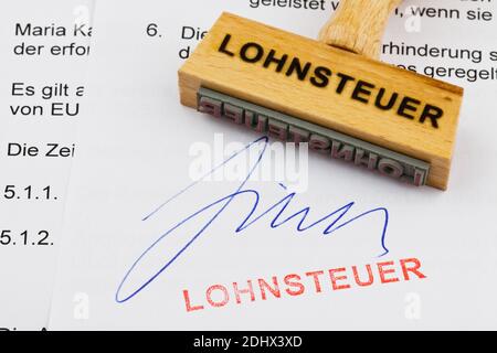 Ein Stempel aus Holz liegt auf einem Dokument. Deutsche Aufschrift: Lohnsteuer Foto Stock