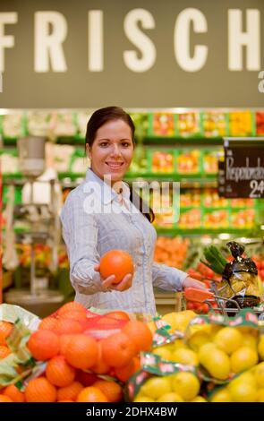 Junge Frau kauft im Supermarkt Lebensmittel und Obst ein, MR: Sì Foto Stock