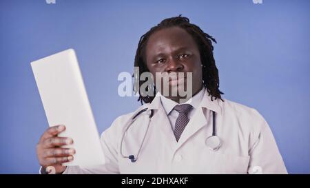 Medico uomo nero che usa la tavoletta per la ricerca medica o la presentazione. Foto di alta qualità Foto Stock