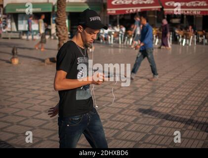 Marrakech, Marocco. 08-10/2018. Jemaa El Fna è la piazza principale e il mercato nel quartiere medina di Marrakech (città vecchia). Giovane che ascolta il suo telefono. Foto Stock