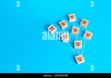 Figurine di legno blocchi di negozi sono interconnessi da linee. Costruire un impero di affari riuscito. Fusione concorrente, creazione di una grande rete m Foto Stock