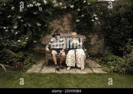 Coppia inglese matura seduta su una panchina godendo il giardino a Antony House, Torpoint, Cornovaglia, Regno Unito. Foto Stock