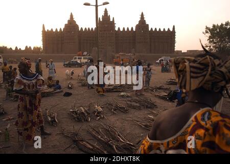 Donne che organizzano legna da ardere di fronte più grande fango mattone o adobe costruzione nel mondo, la Grande Moschea di Djenné in Mali, Africa occidentale. Foto Stock