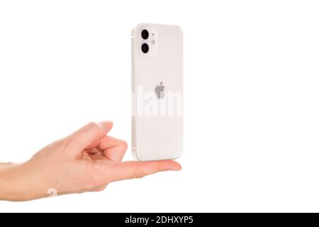 Bratislava, Slovacchia - 07 dicembre 2020. Mano femminile che presenta il nuovo iPhone 12 bianco isolato su sfondo bianco. Foto Stock