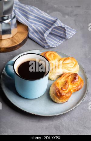 Tazza di caffè espresso con due ciambelle dolci a forma di cuore in piastra su fondo grigio in cemento. Una vita still minimalista. Foto Stock