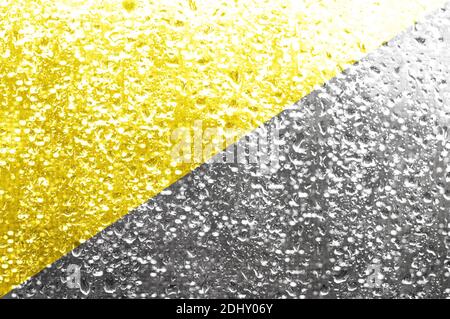 Illuminante sfondo giallo e grigio finale . 2021 colori alla moda. Gocce sul vetro del finestrino. Foto Stock