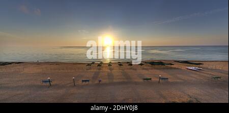 Ombrelloni da spiaggia all'alba. La corrente del mare nuota contro le onde sul mare bello Foto Stock