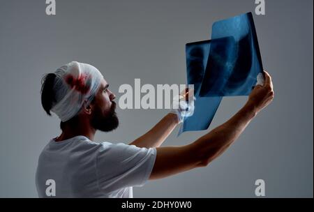 il paziente con una testa a banda esamina i raggi x su un grigio medicina di base Foto Stock