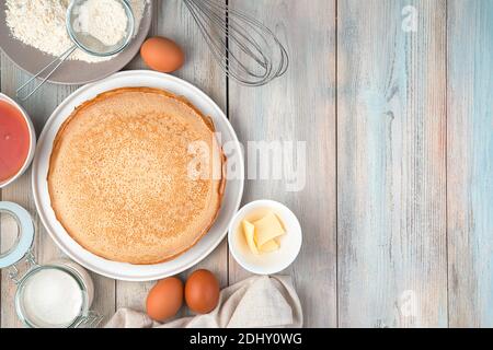 Piatto con frittelle, uova, farina, burro, miele su sfondo chiaro. Foto Stock