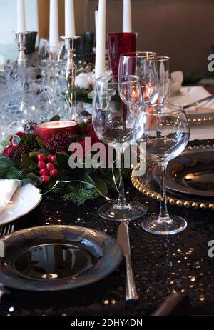 Composizione di natale di rami di abete, le bacche e le candele sul tavolo. Festosa messa in tavola per la cena di Natale su un lucido nero tovaglia e ex Foto Stock