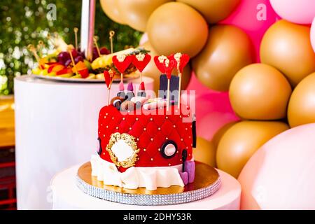 Soft focus. Una splendida torta decorata con rossetti e cuori per il compleanno di una giovane ragazza. Candy bar con dolci, frutta, decorazione con balloo Foto Stock