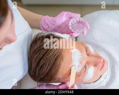 Cosmetici maschili. Un uomo dall'aspetto bello che riceve un trattamento viso presso una lussuosa spa Foto Stock