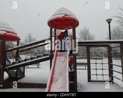 Mortara - 12-04-2020: Bambini che giocano nel parco giochi sotto la neve nel nord Italia Foto Stock