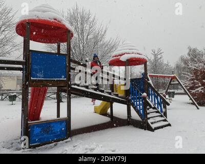 Mortara - 12-04-2020: Bambini che giocano nel parco giochi sotto la neve nel nord Italia Foto Stock