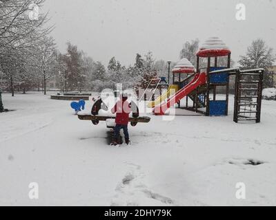 Mortara - 12-04-2020: Bambini che giocano nel parco giochi sotto la neve nel nord Italia Foto Stock