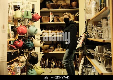 Lo shopper mascherato in una giacca invernale passa accanto alla rastrelliera per teiera nel piccolo negozio di cucina di Ottawa, Ontario, Canada. Foto Stock