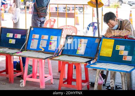 Provincia di Chonburi, Thailandia - 25 settembre 2020, Lottery Saller sedette in fila e aspetta il compratore accanto alla strada di fronte al mercato del pesce Angsila, la lar Foto Stock