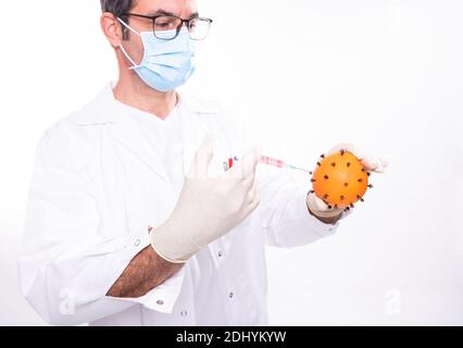 medico con il facciale filtrante facendo una vaccinazione contro un virus (cioè un arancione) Foto Stock