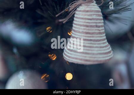 primo piano di campana appesa all'albero di natale con luci acceso Foto Stock