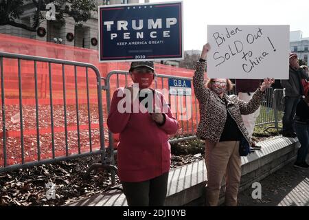 Atlanta, Georgia, Stati Uniti. 12 dicembre 2020. In occasione di un raduno pro-Trump ad Atlanta, due manifestanti hanno dei segnali che leggono IL PENCE DI TRUMP: KEEP AMERICA GREAT e BIDEN SOLD OUT TO CHINA! Fuori dal Campidoglio dello stato della Georgia. Il rally si è svolto un giorno dopo che la Corte Suprema degli Stati Uniti ha respinto una causa depositata dallo stato del Texas, chiedendo alla corte di rovesciare i risultati delle elezioni in Georgia, Pennsylvania, Michigan e Wisconsin; quattro stati di battaglia che sono stati vinti dal presidente eletto Joe Biden nelle elezioni presidenziali del 2020. Credit: John Arthur Brown/ZUMA Wire/Alamy Live News Foto Stock