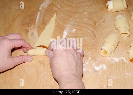 Fare biscotti fatti in casa. Torcendo l'impasto affettato con la marmellata con le mani delle donne prima di cuocere. Messa a fuoco selettiva. Foto Stock