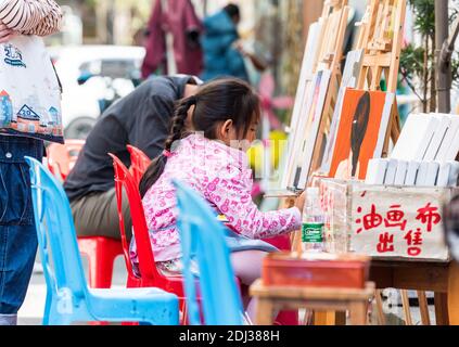 Una bambina cinese dipinto su tela nel villaggio di pittura di Dafen Oil, Shenzhen, provincia di Guangdong, Cina Foto Stock