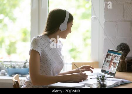 Primo piano giovane donna che indossa le cuffie che studia online con l'insegnante Foto Stock