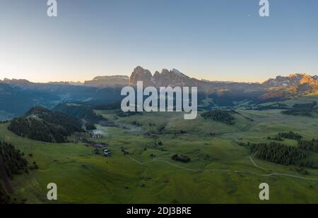 Drone shot, Alpe di Siusi con prati e capanne di fronte a Sassolungo e Sassolungo, alba, Alpe di Siusi, Alto Adige, Italia Foto Stock