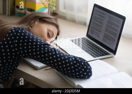 Primo piano, giovane donna stanca che si addormenta alla scrivania Foto Stock