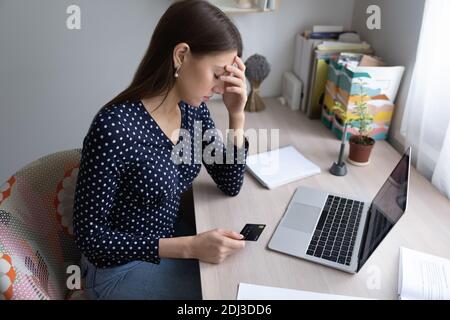 Infelice donna frustrata tenendo carta di plastica, avendo problemi con i soldi Foto Stock