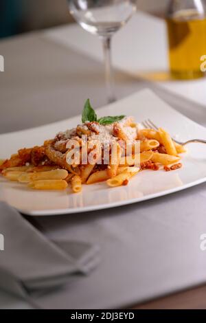 Messa a fuoco selettiva e primo piano di un piatto appetitoso di maccheroni con salsa bolognese e formaggio grattugiato. Pasta e stile di vita. Foto Stock