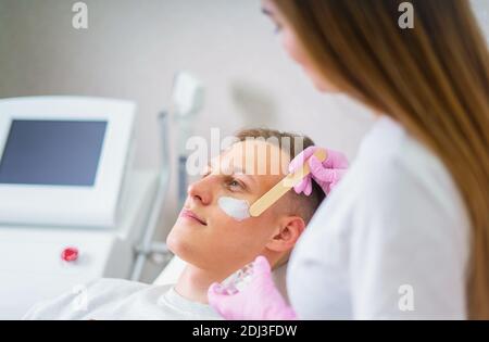 Cosmetici maschili. Un uomo dall'aspetto bello che riceve un trattamento viso presso una lussuosa spa Foto Stock