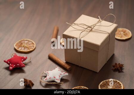 Confezione regalo di Natale di carta ecologica avvolta con spago naturale su tavola di legno con decorazioni naturali, messa a fuoco superficiale
