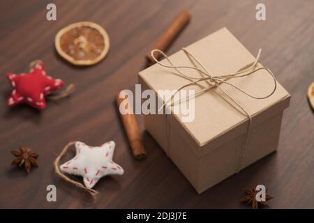 Confezione regalo di Natale di carta ecologica avvolta con spago naturale su tavola di legno con decorazioni naturali, messa a fuoco superficiale