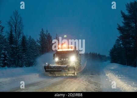 Lapponia, Svezia: Vista notturna di uno spazzaneve in una strada deserta e ghiacciata, coperta di neve, in Lapponia Foto Stock