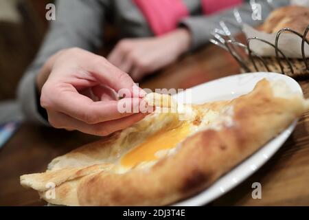 Persona ha Khachapuri Adjarian in ristorante georgiano Foto Stock