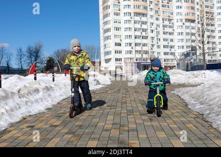 Due fratelli che cavalcano nel parco giochi in primavera Foto Stock